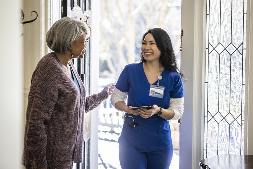 Mature person greeting home nurse care team member at front door of home