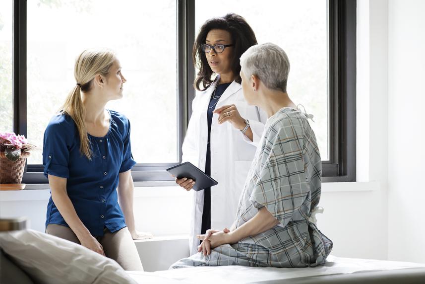 Doctor having discussing with mature patient and her daughter in hospital 