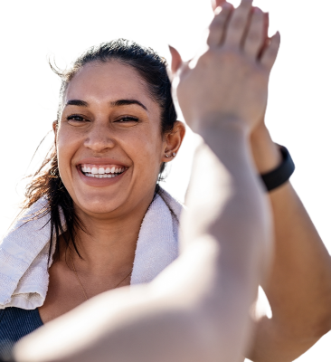 A women with a gym towel around her shoulders recieving a high five from someone not in the image. 