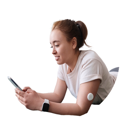 A girl laying on a bed looking at her smart phone. She has a visible medical patch on her arm.