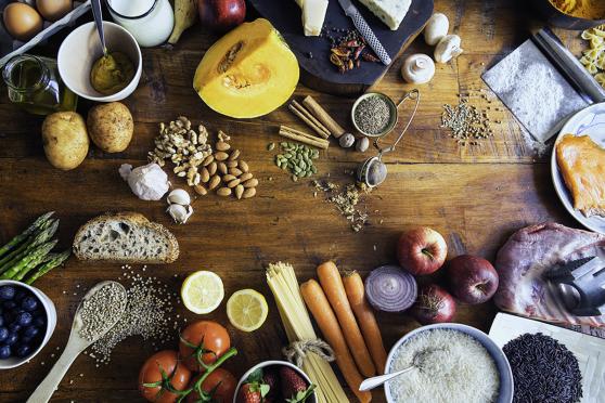 Colorful and healthy table composed with fruits and vegetables of many different types, meat, cheese, eggs, fish, spices and grains on wooden rustic table, view from above