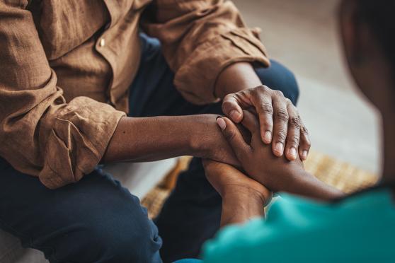 Closeup of two people holding hands for support