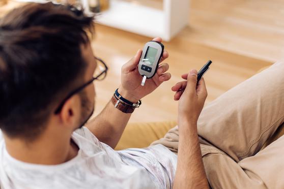 Young man measuring his glucose level at home